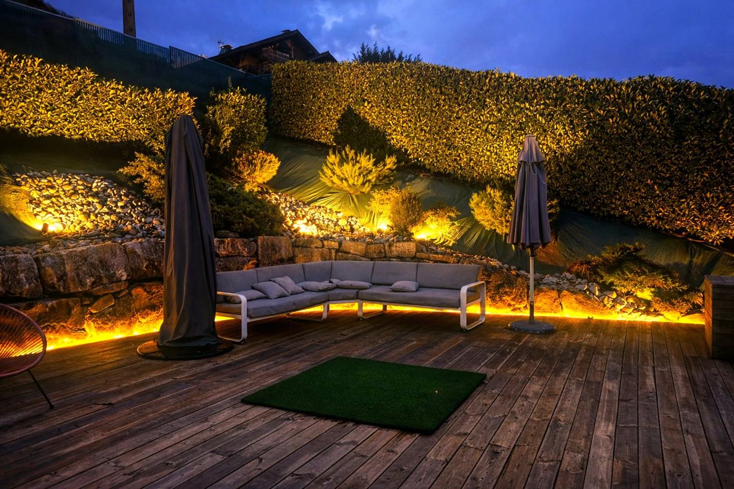 Terrasse paysagère alpine éclairée à l'heure bleue, salon d'extérieur